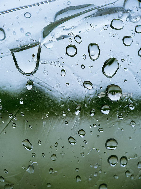 雨滴落在窗户上，模糊了背景中的风景