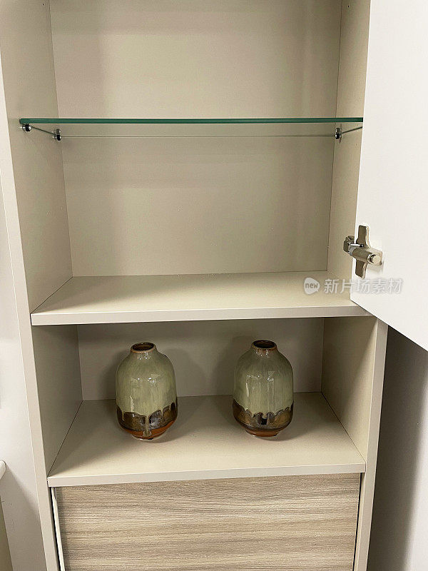 门开的橱柜形象，木制的橱柜，玻璃架子展示绿色的釉面花瓶