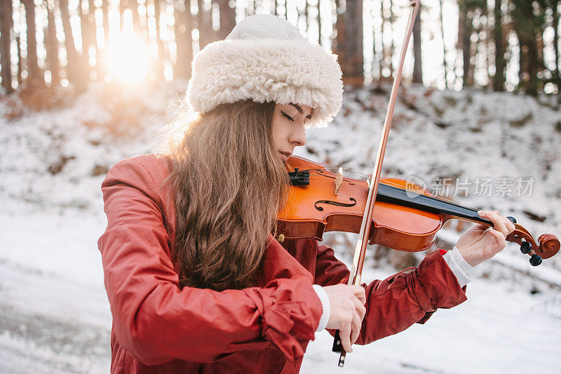 一位年轻女子在一个下雪天拉小提琴