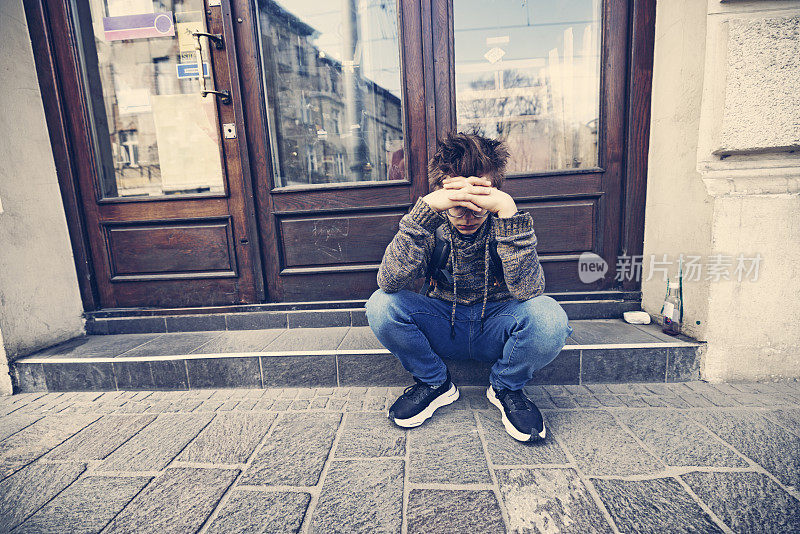 沮丧的少年坐在街上