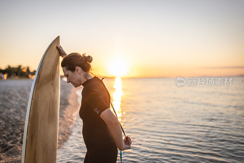 沙滩上拿着冲浪板的女人