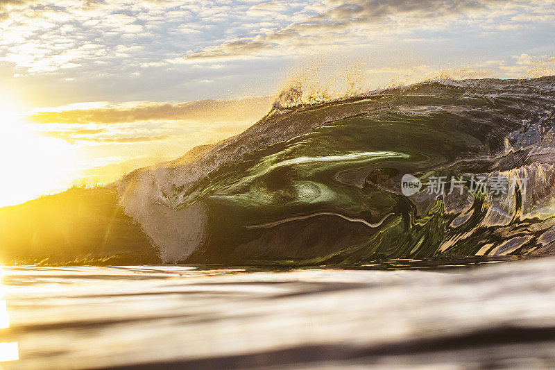 巨大而有力的海浪涌上浅浅的礁石平台，发出明亮的金色光芒