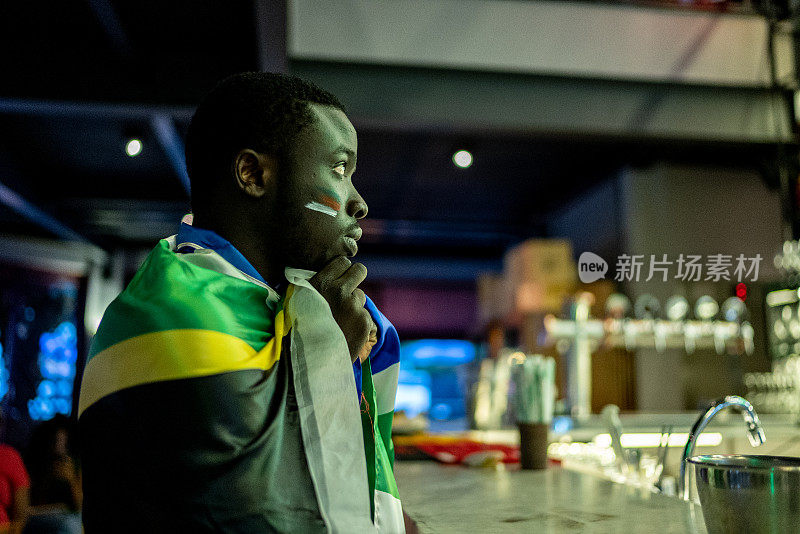 一个年轻人在酒吧里看运动队比赛