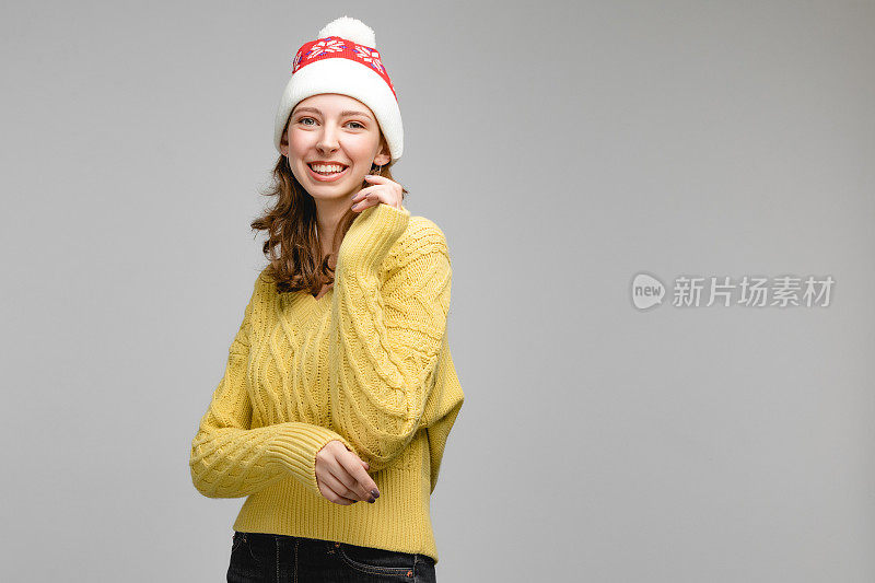 圣诞妇女肖像的女孩戴着圣诞老人的帽子，人手势的相机和显示的情绪。工作室概念与人在灰色背景和复制空间。新年摄影