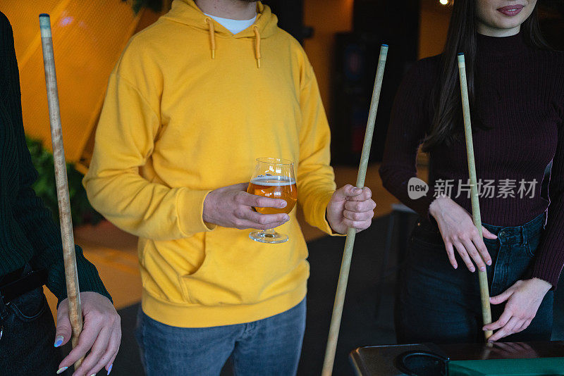 面目全非的男子拿着啤酒杯，等着坐台球桌