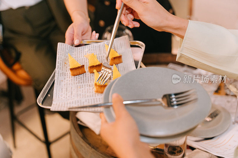 在室内聚会中，女性用叉子拿甜点和甜点芝士蛋糕