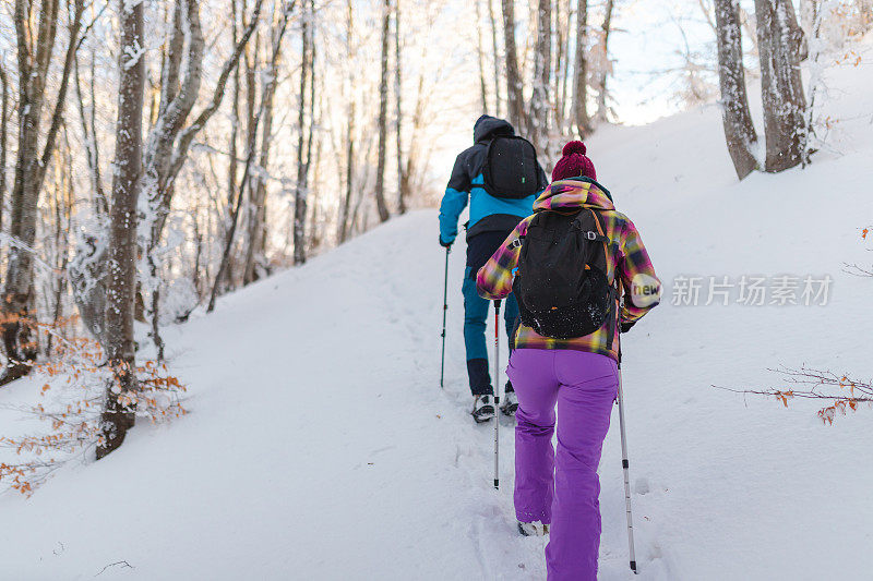 两个年轻的徒步旅行者在冬天爬上雪山