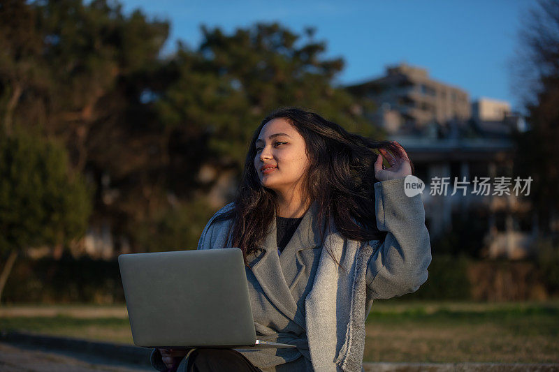 年轻的学生女孩正在外面学习。