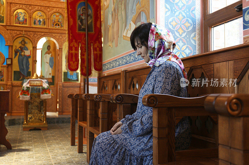 成熟的女人坐在教堂的木凳上