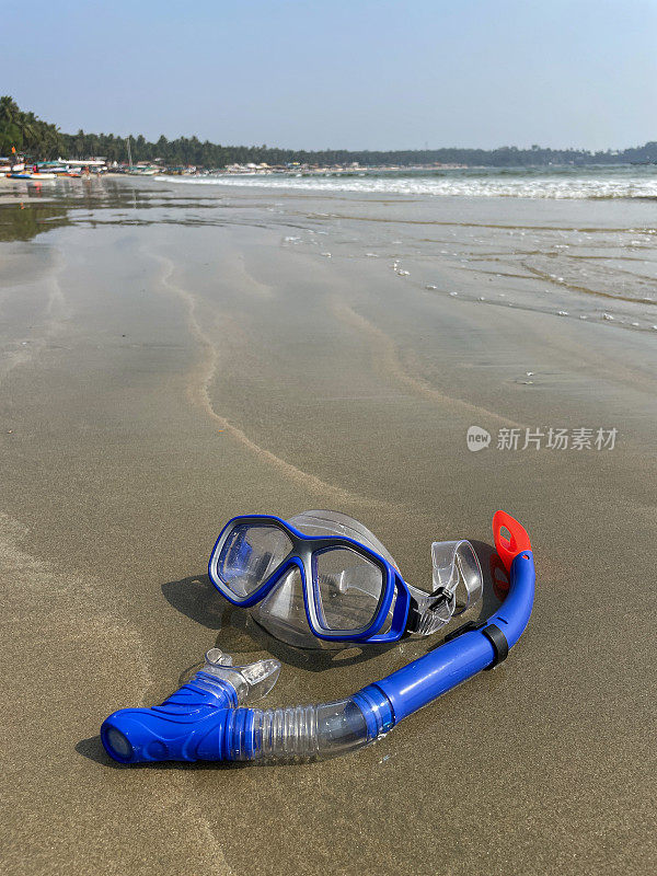 水肺面罩和浮潜的图像，在退潮时留在沙滩上，破碎的海浪在海岸上，海的背景，重点在前景，复制空间