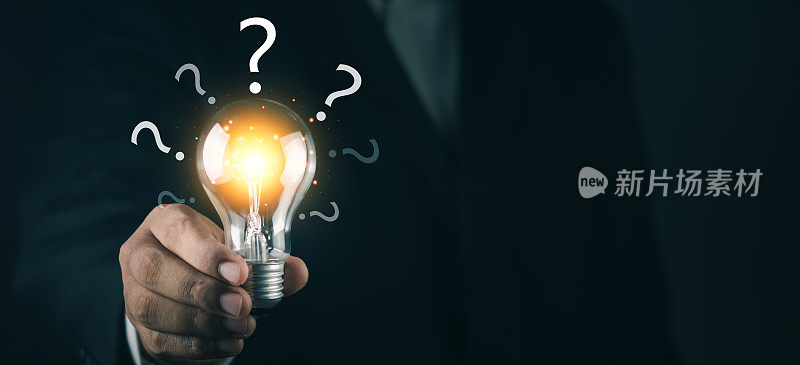 发光的灯泡和带有复制空间的问号。商人拿着发光的灯泡和问号代表创造性思维和解决问题的概念。