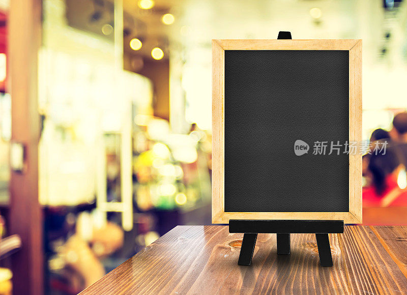 模糊的咖啡店背景木桌上的带有画架的黑板，模拟展示或蒙太奇设计用于网上购物促销
