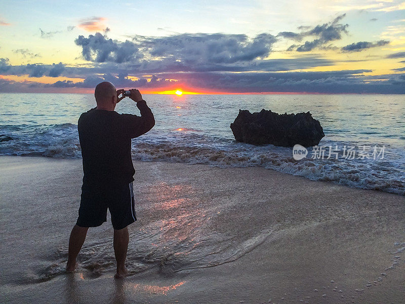男子在百慕大海滩上拍摄日出
