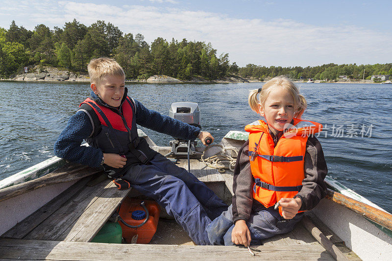 两个穿着救生衣的小男孩在一艘小船上。