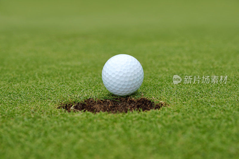 高尔夫球，球躺在洞旁的果岭上