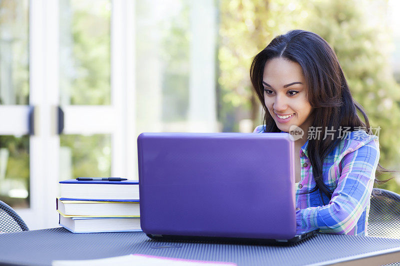 一个年轻的女学生在用紫色的笔记本电脑