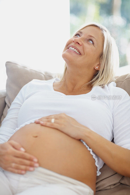 孕妇在家里抱着肚子向上看