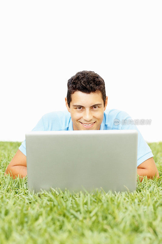 英俊快乐的家伙在草地上用笔记本电脑