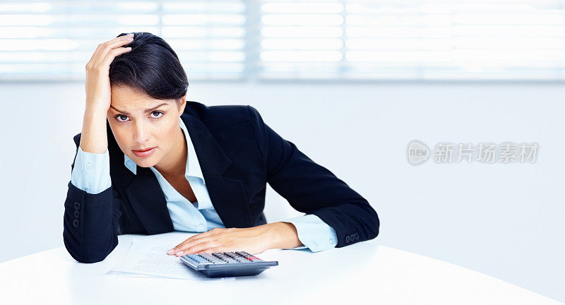 紧张的商务女性在工作中使用计算器