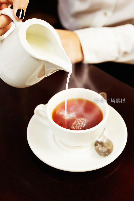 喝杯好茶吧!女性手加牛奶。