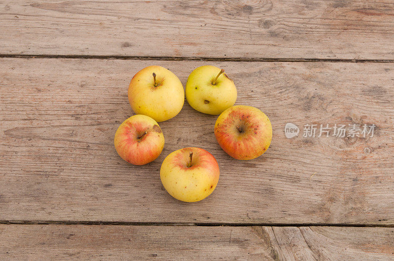 五个苹果放在一张简陋的木桌上