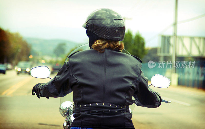 穿着黑色齿轮的摩托车骑手在街上游弋