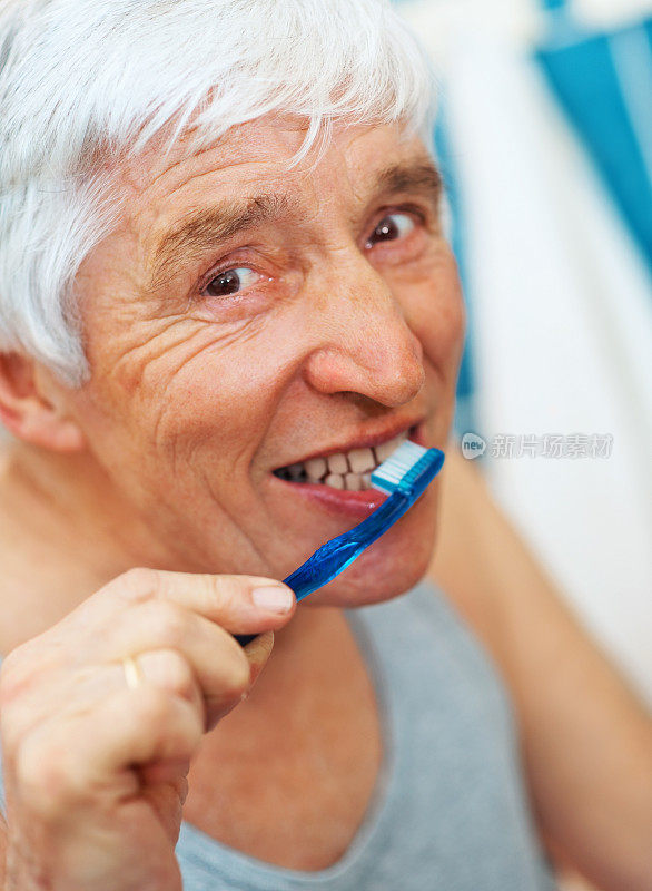 一个白色头发的男人正在刷牙的特写