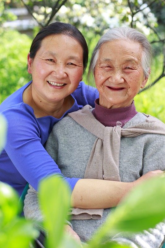 年长的亚裔妇女和她的女儿在院子里