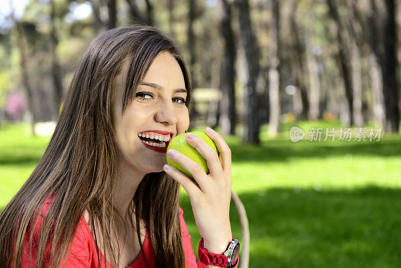 美女在户外运动后吃苹果。