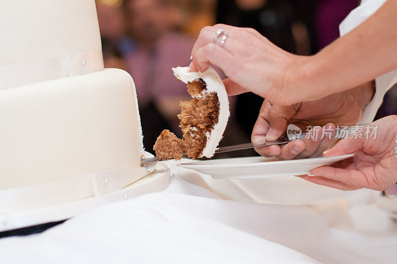 新郎和新娘正在切带戒指的白色婚礼蛋糕