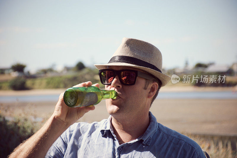 男子在海滩边喝着啤酒放松