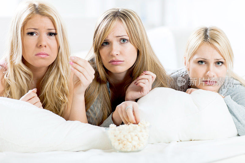 年轻女人躺在床上看悲伤的电影。