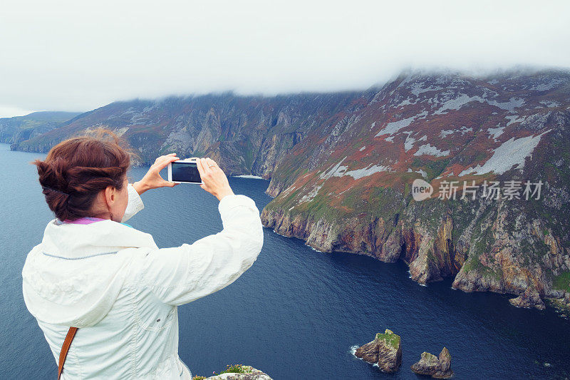 一名女子正在拍摄岩壁联盟悬崖的照片