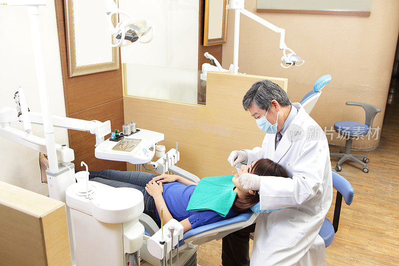 在牙科治疗中有牙医和助手的女病人
