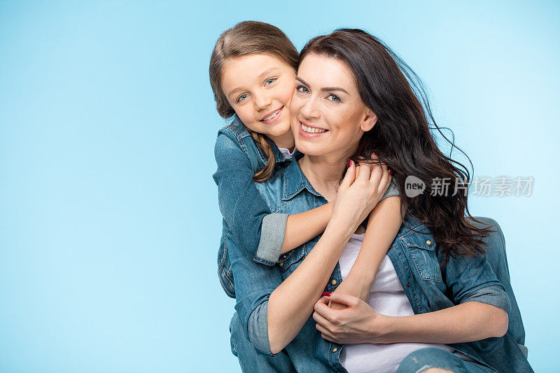幸福的母亲和女儿拥抱在工作室蓝色的肖像