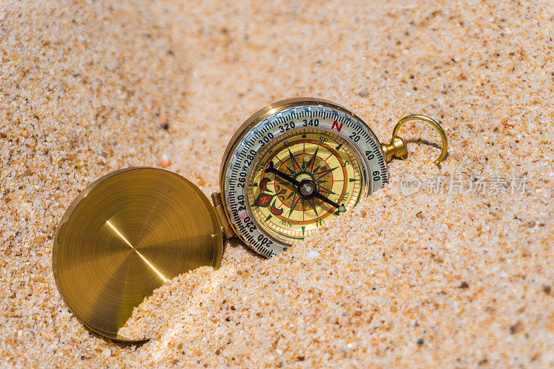 指南针在沙滩上的金色沙滩上。夏天的时间