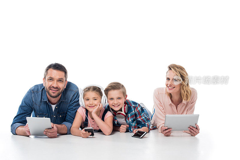 微笑的家庭与各种数码设备看着孤立在白色的相机
