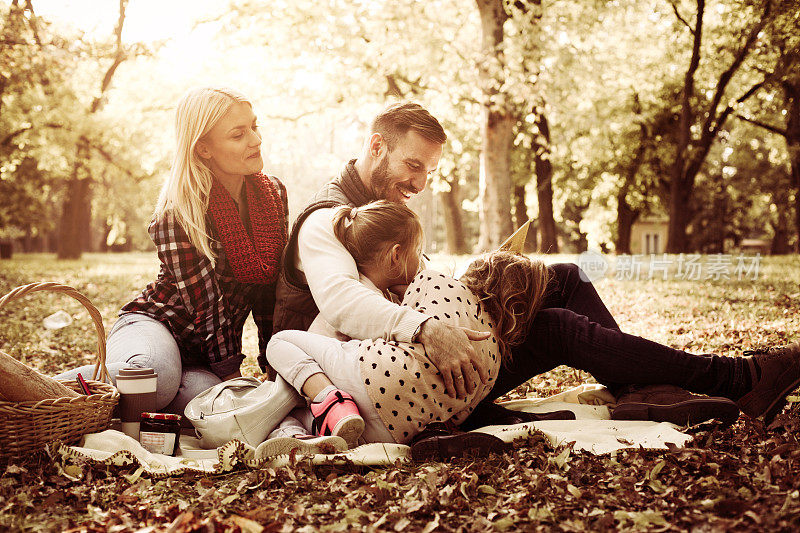 快乐的家庭野餐和父亲读书给他的小女儿。