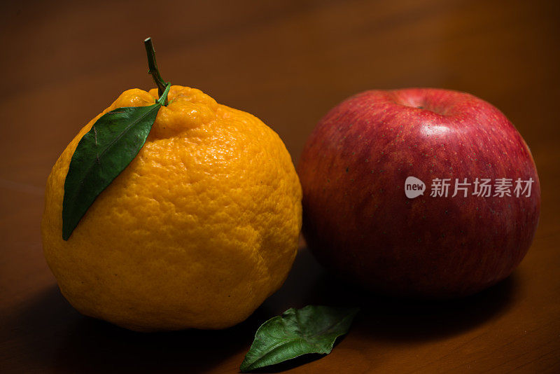 木制背景上的日本有机橘子和红苹果