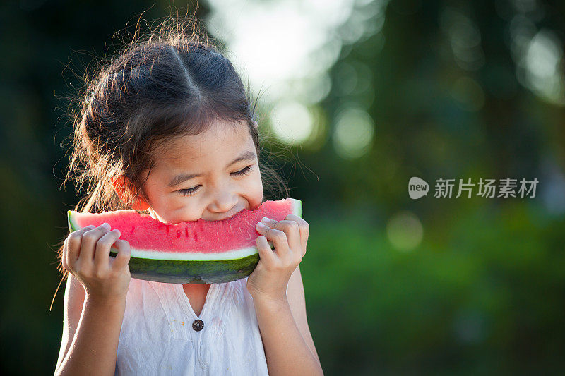 可爱的亚洲小女孩吃西瓜新鲜水果在花园里