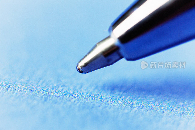 圆珠笔悬停在蓝色纸上的极端特写