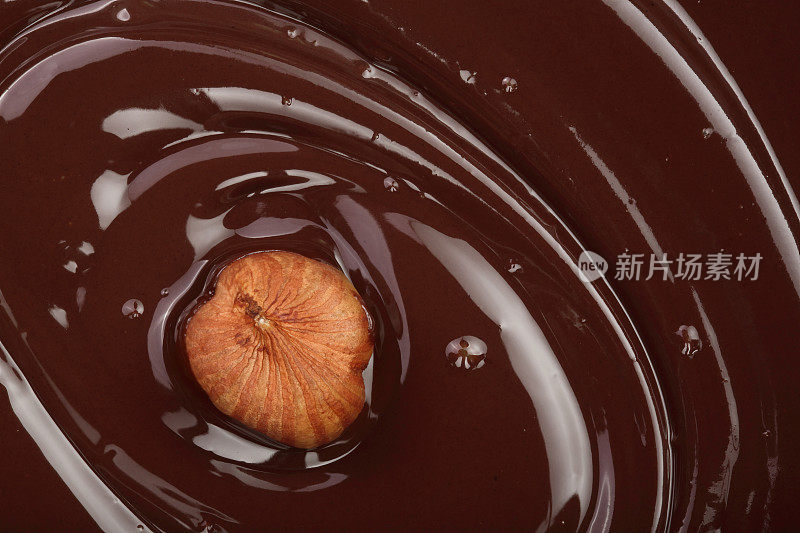 融化的巧克力漩涡与榛子作为背景特写
