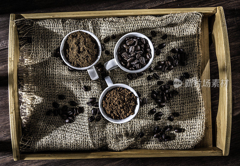 三杯咖啡豆，速溶咖啡和研磨咖啡在木托盘与黄麻