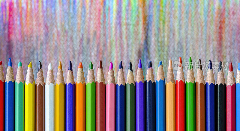 许多色彩鲜艳的彩色铅笔或蜡笔排成一排，用戴着的蜡笔头作了一个彩色的阴影画背景，这是蜡笔后面的特色。