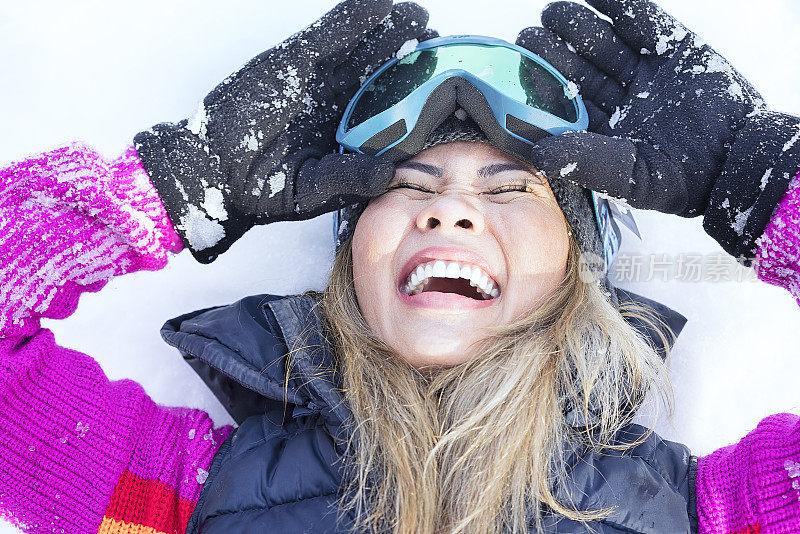 戴着滑雪镜在雪地上笑的女人