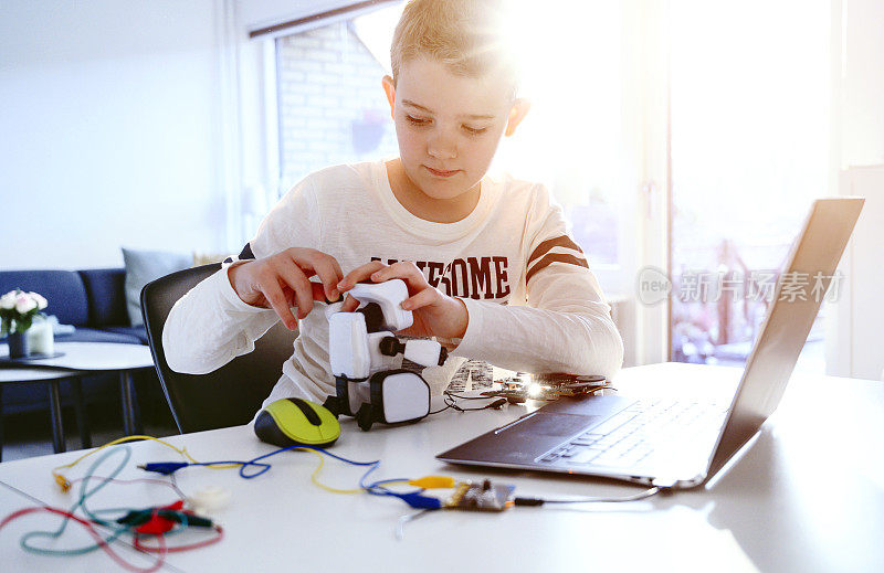 快乐的孩子在玩他用电子设备和笔记本电脑制作的机器人