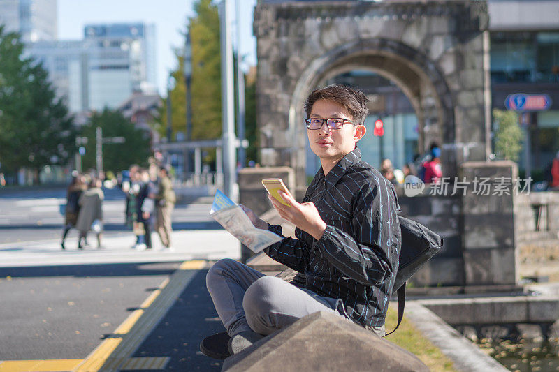 年轻的亚洲男子和日本朋友寻找旅游地点使用手机和花时间在亚洲旅行