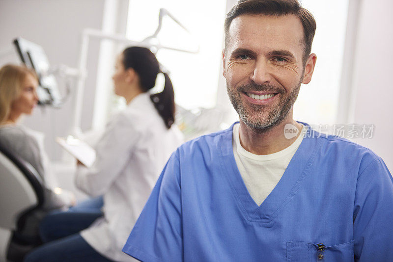 在牙科诊所微笑的男牙医正面视图