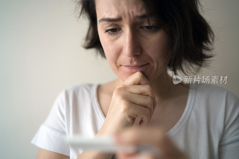 一位忧心忡忡的年轻女子正在看她的验孕结果