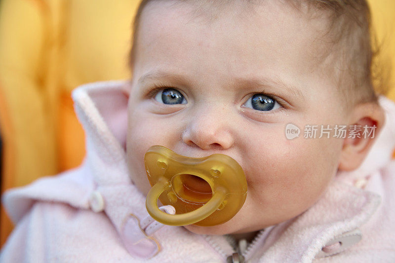 脸部特写的一个快乐的婴儿与奶嘴看镜头